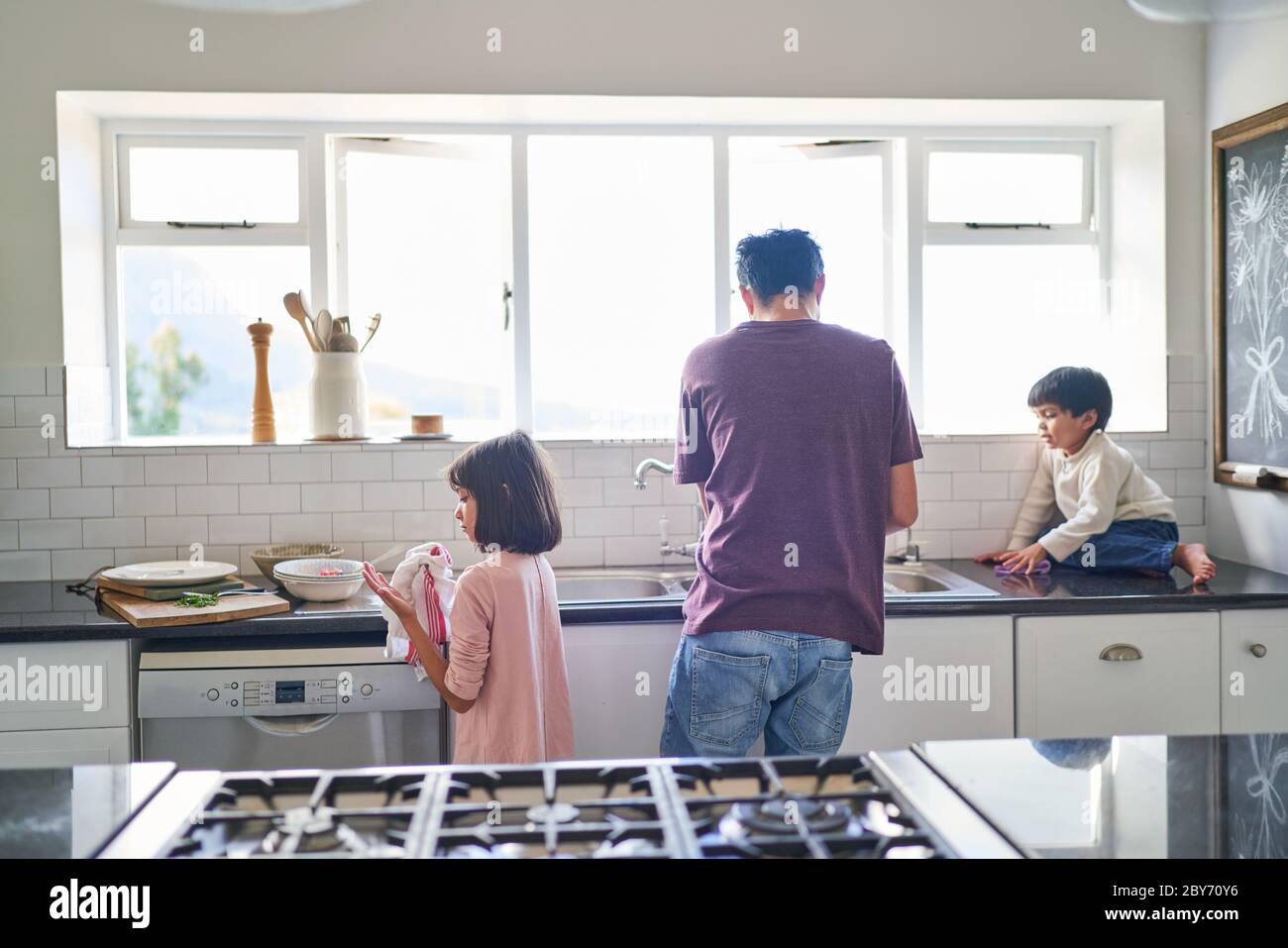 Familia haciendo platos en el fregadero de la cocina Foto de stock