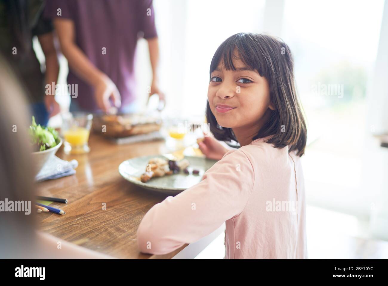 Retrato niña feliz comer con la familia en la mesa Foto de stock