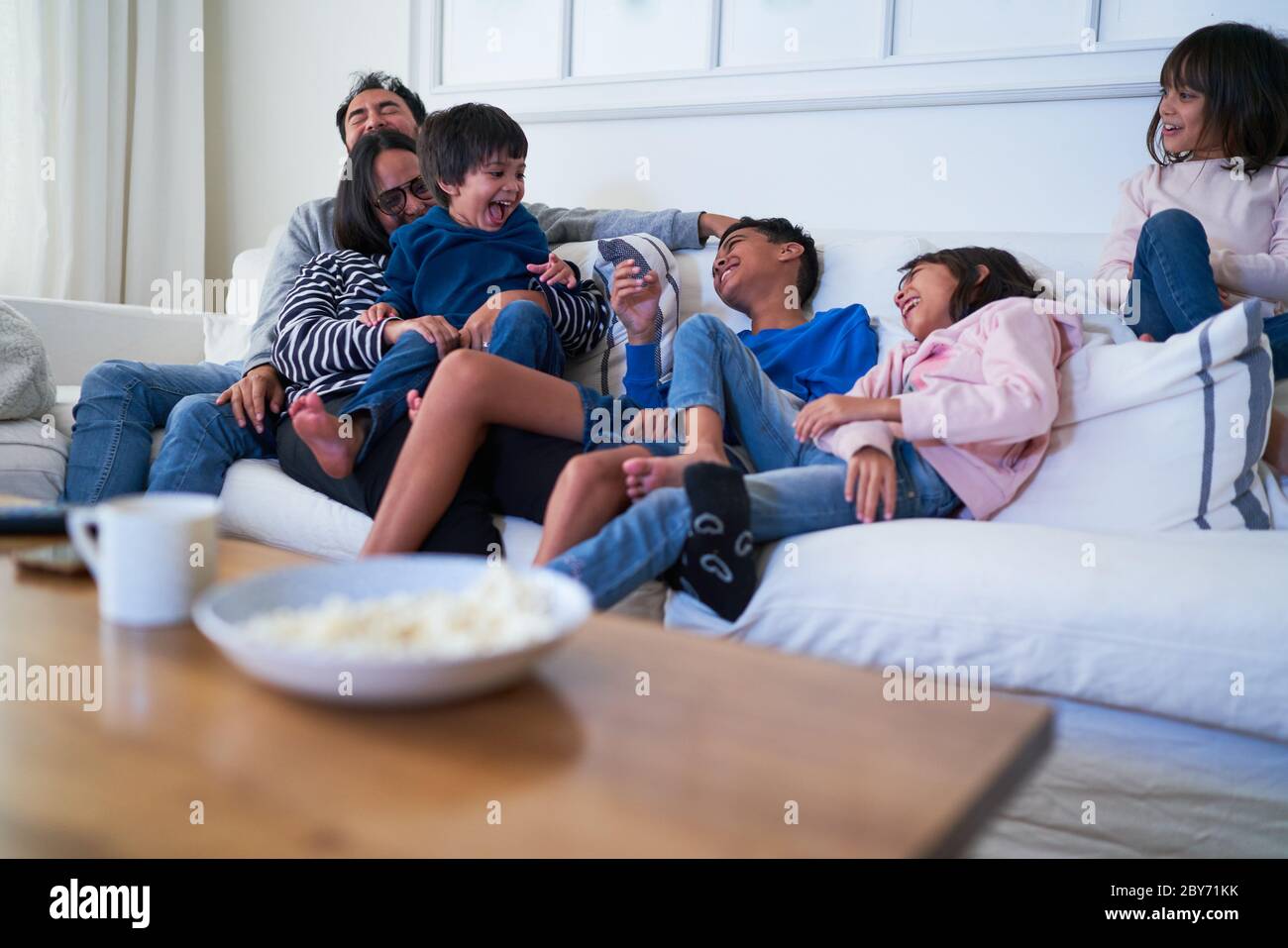 Familia juguetona en el sofá de la sala de estar Foto de stock