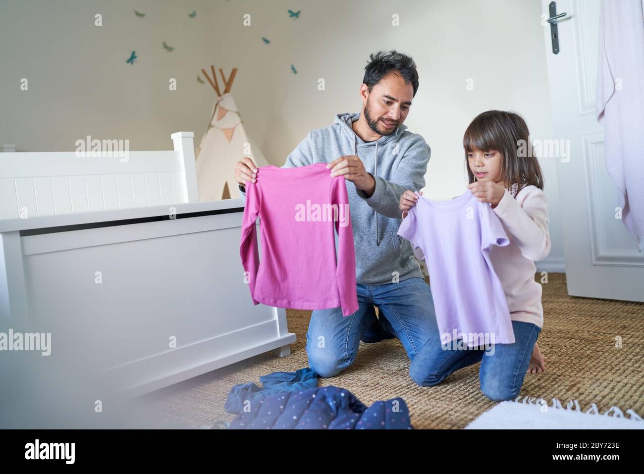 Padre e hija ropa plegable en el dormitorio Foto de stock