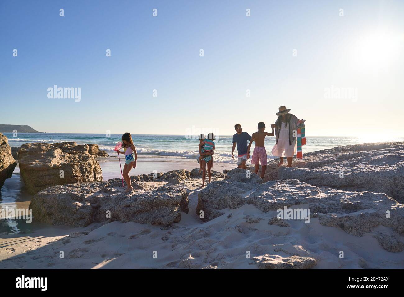 Familia jugando en rocas en la soleada playa del océano, Ciudad del Cabo, Sudáfrica Foto de stock