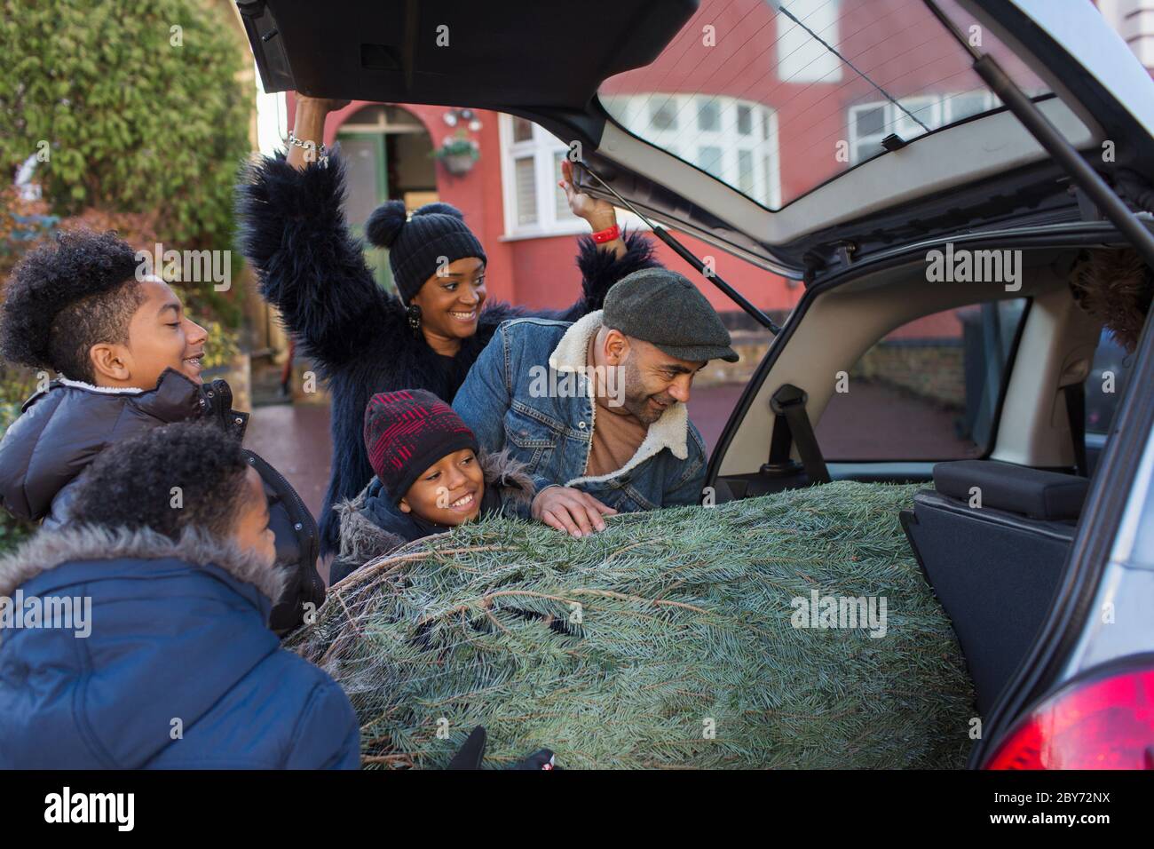 Familia cargando árbol de Navidad en el coche Foto de stock
