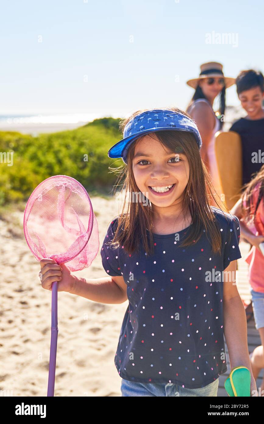 Retrato niña feliz con red de pescado en la playa soleada Foto de stock