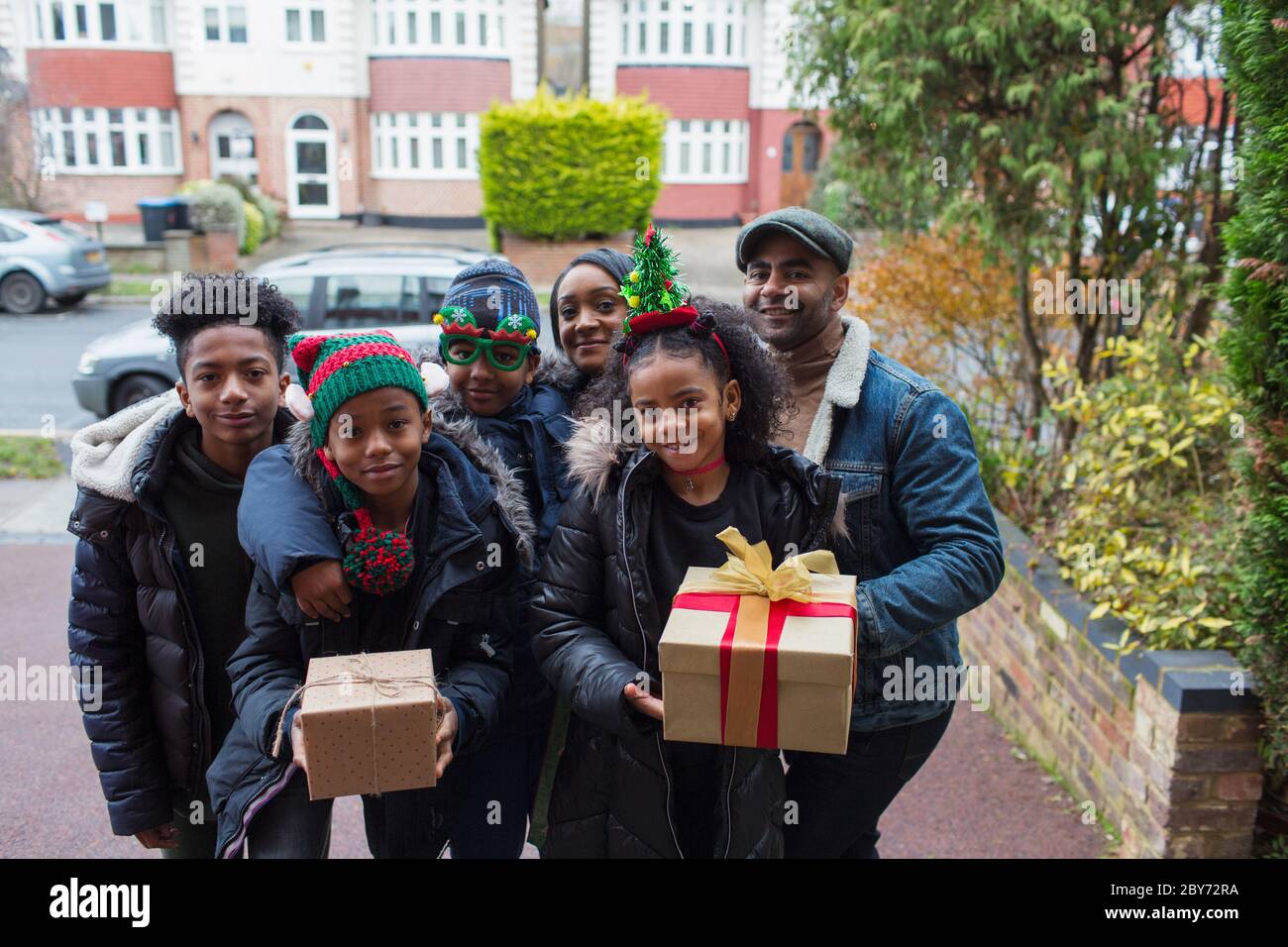 Retrato feliz familia con regalos de Navidad en la entrada Foto de stock