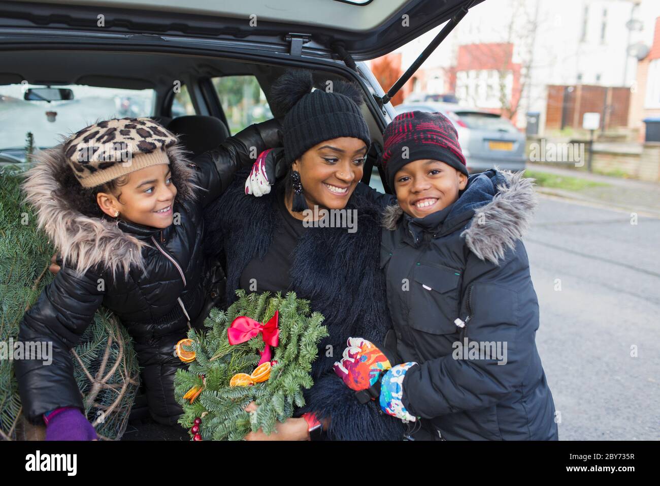 Retrato feliz familia con corona de Navidad en la parte trasera del coche Foto de stock