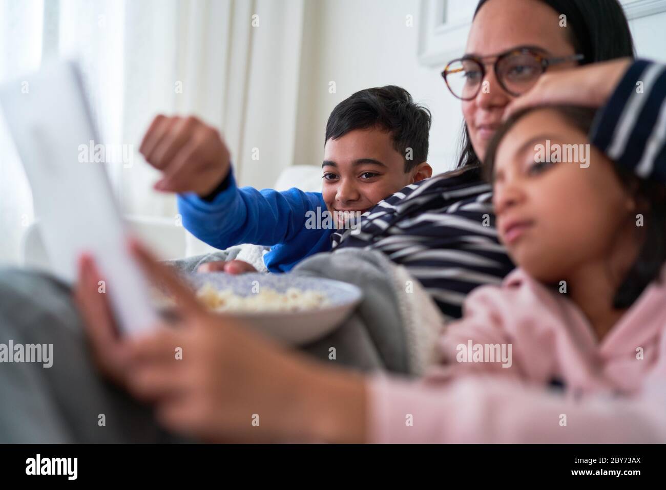 Madre y niños con palomitas viendo películas en tabletas digitales Foto de stock