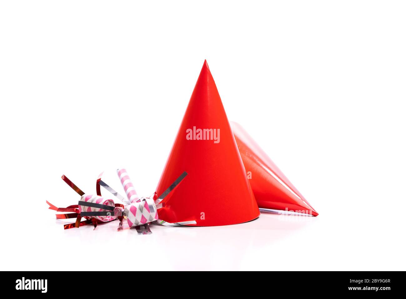 Sombreros de cumpleaños rojos y fabricantes de ruido sobre un fondo blanco. Foto de stock