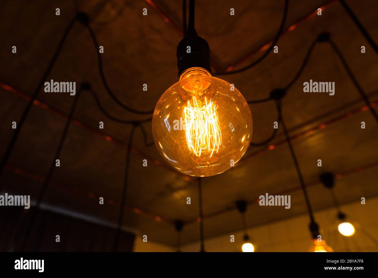 Grandes bombillas incandescentes vintage colgando en la cocina moderna. Las bombillas de filamentos ineficientes desperdician electricidad. Regulable, blanco cálido, E27 Foto de stock