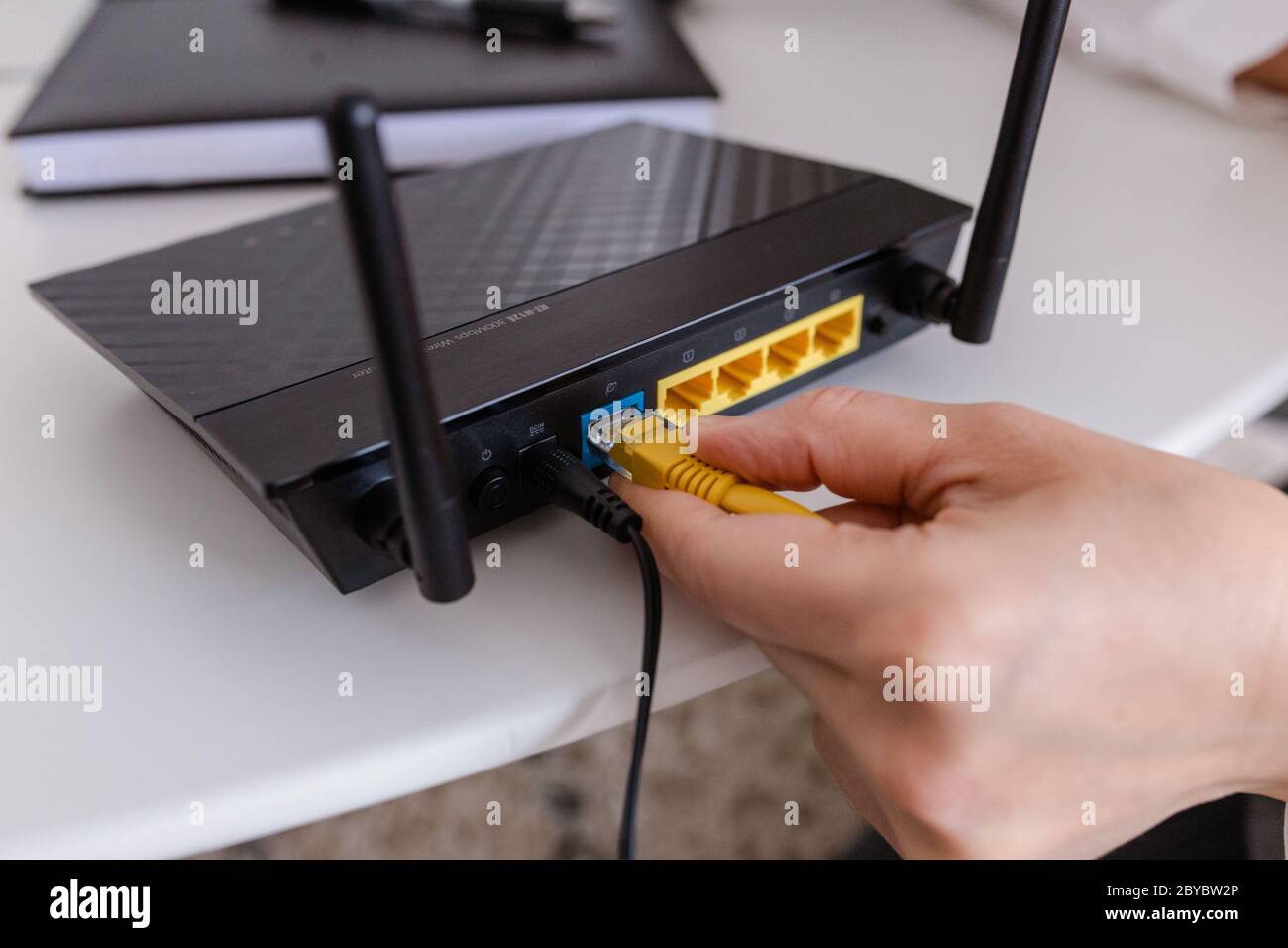 mujer conecta el cable de internet a la toma del router. Conexión a internet rápida e inalámbrica Foto de stock