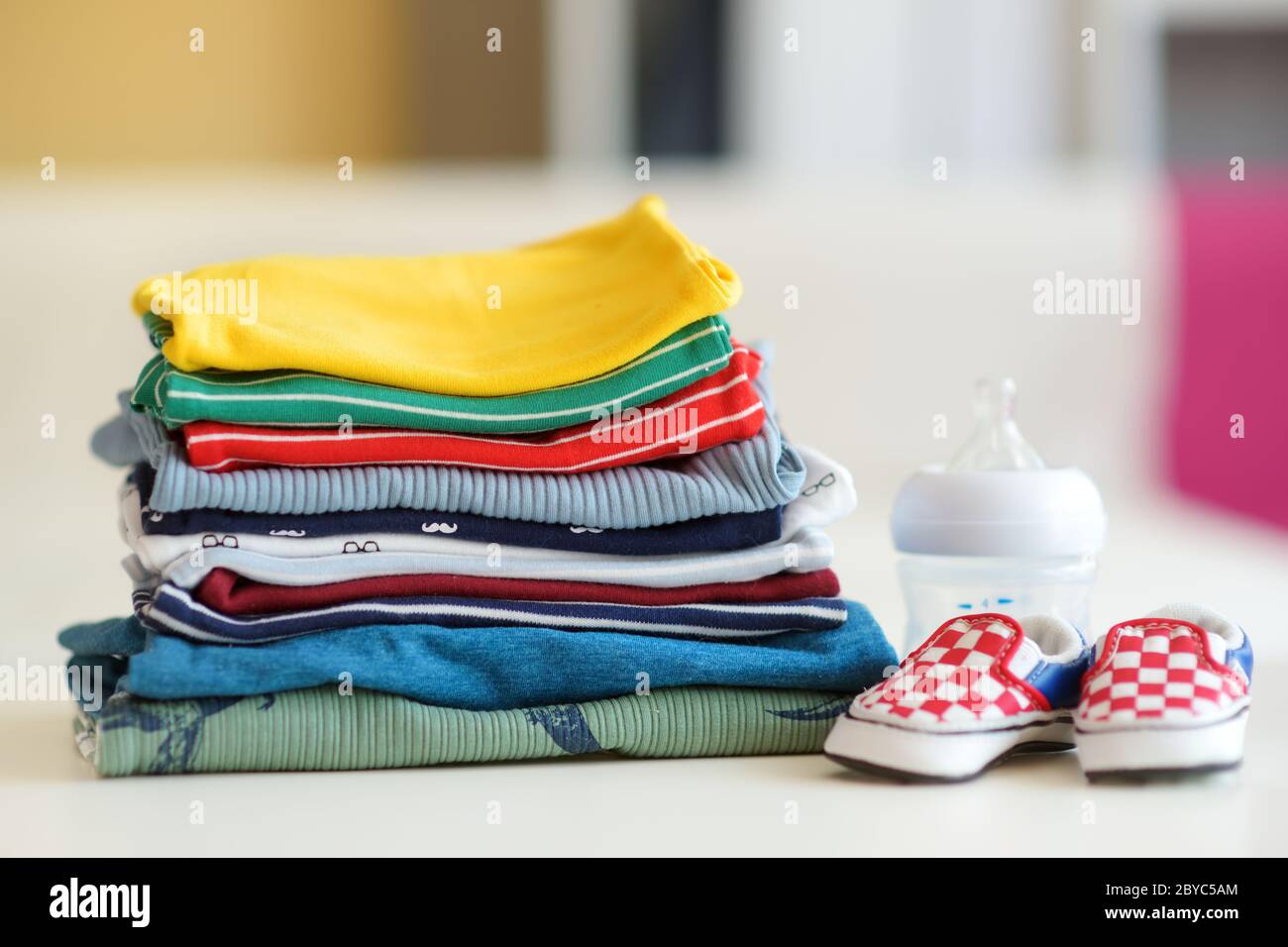 Un montón de ropa para bebés, biberón y zapatos para recién nacidos. Concepto de gastos de crianza. Trabajando un presupuesto para bebés. Ahorrar dinero al planificar Foto de stock