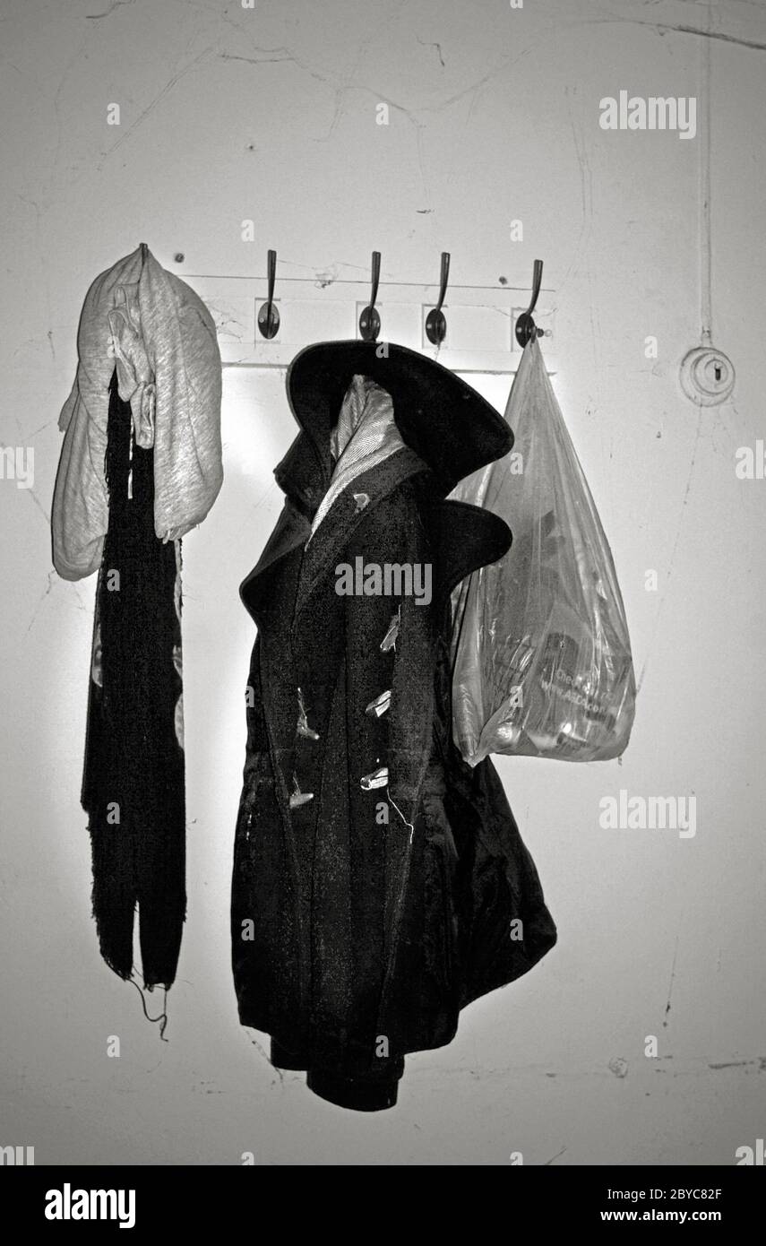 abrigo viejo, sudorshsirt y bolsa de plástico, abandonado en la percha de la vendimia en el edificio en desuso Foto de stock