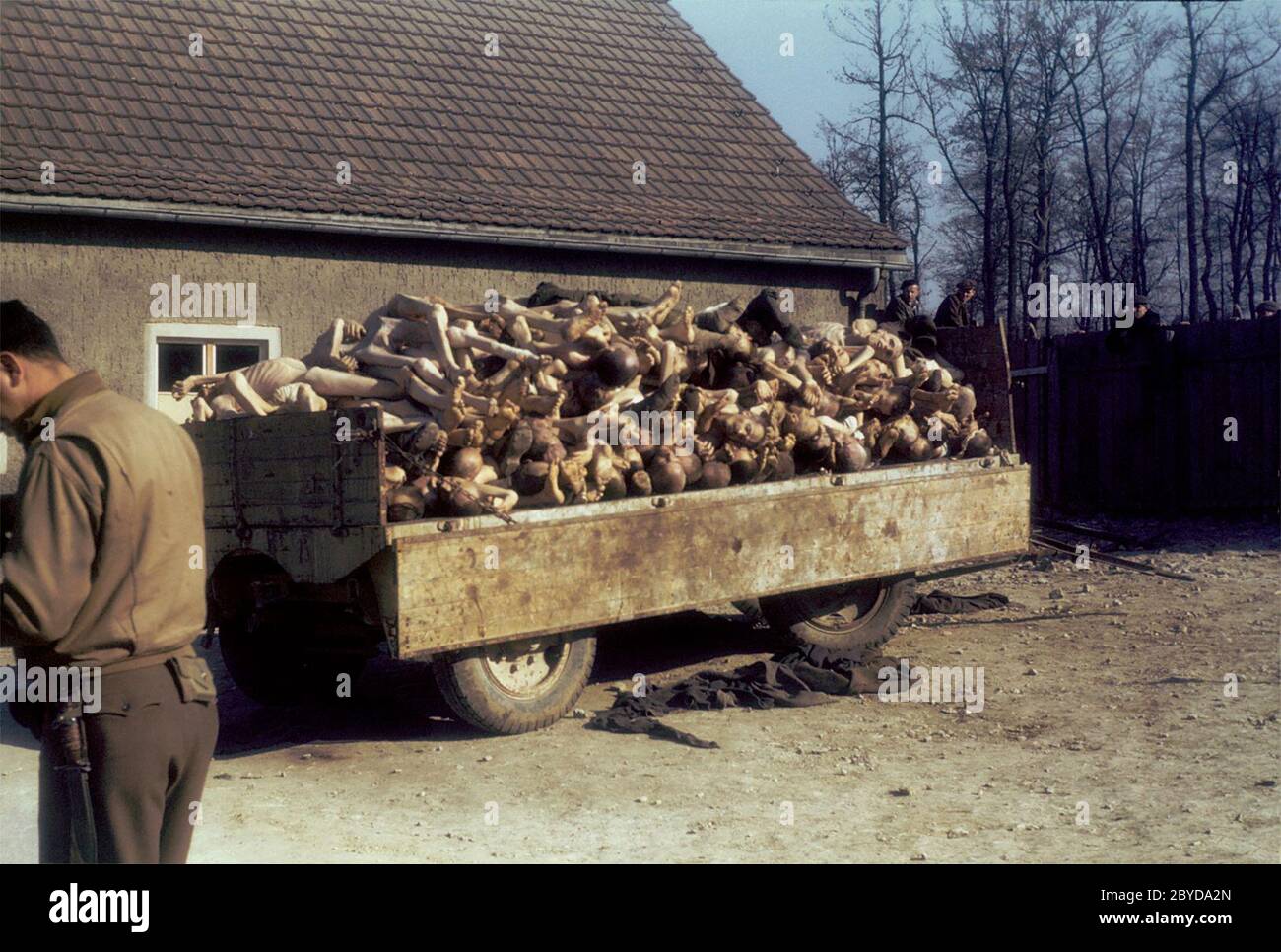 Un soldado americano se encuentra cerca de un vagón cargado de cadáveres fuera del crematorio del campo de concentración de Buchenwald, Alemania, tras su liberación. 16 de abril de 1945 Foto de stock