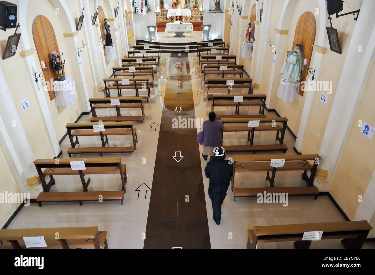 Quito, Ecuador. 9 de junio de 2020. Una mujer sigue las flechas que apuntan el camino a la iglesia de Loya, al sur de Quito, seguida por un voluntario que comprueba que Quito, Ecuador. 9 de junio de 2020. Una mujer sigue las flechas que apuntan el camino a la iglesia de Loya, al sur de Quito, seguida por un voluntario que comprueba que