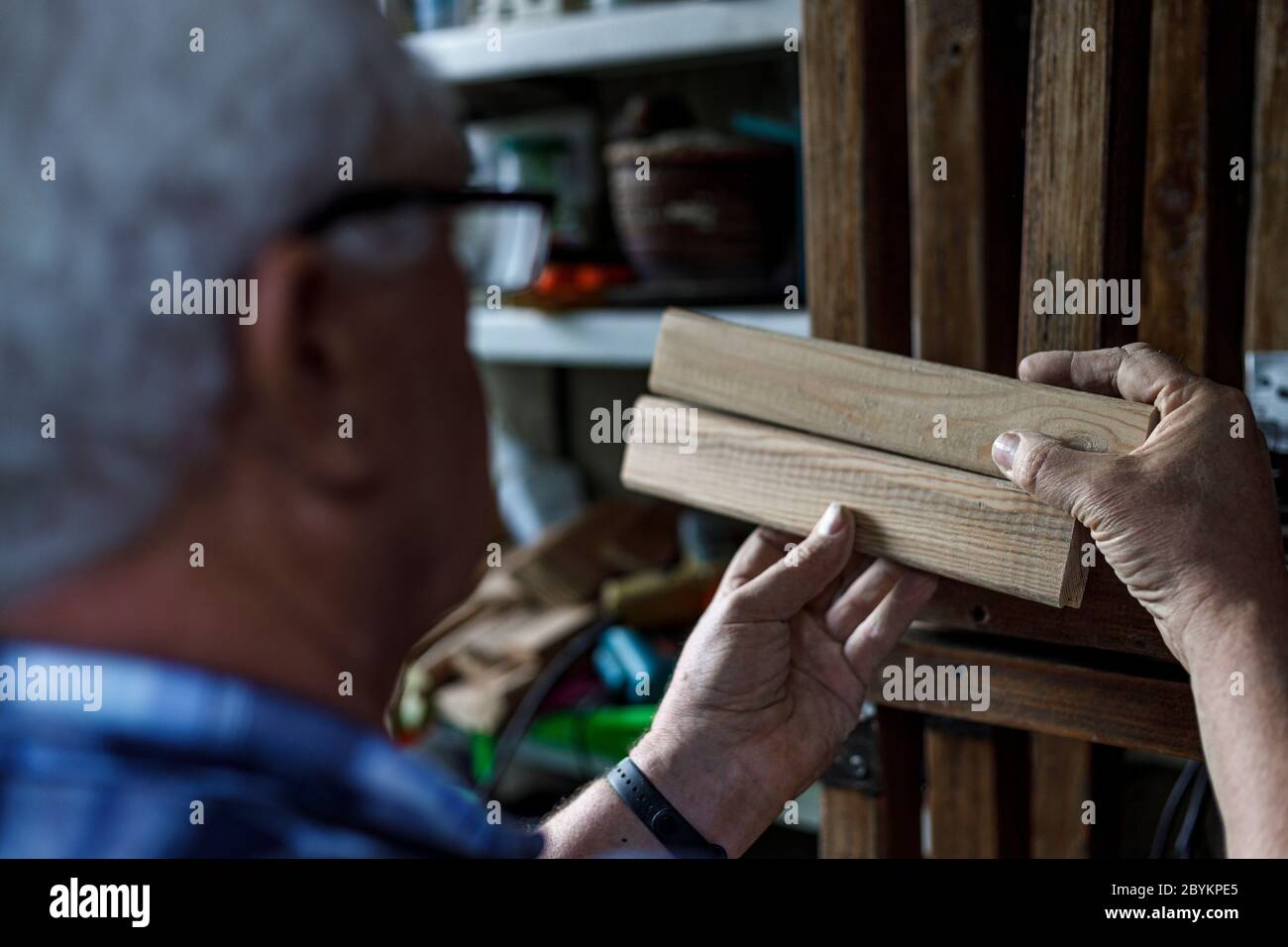 Viejo carpintero que comprueba los tablones de madera. Foto de stock
