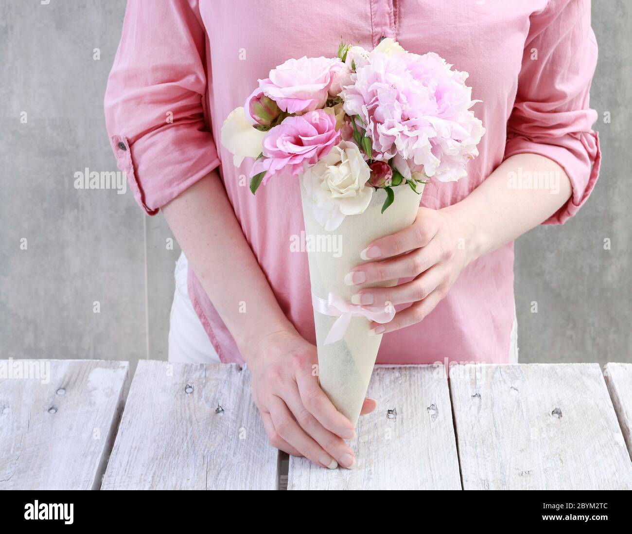 Floristería en el trabajo: Mujer muestra quién debe organizar las flores  dentro de un corneta de papel. Paso a paso, tutorial Fotografía de stock -  Alamy