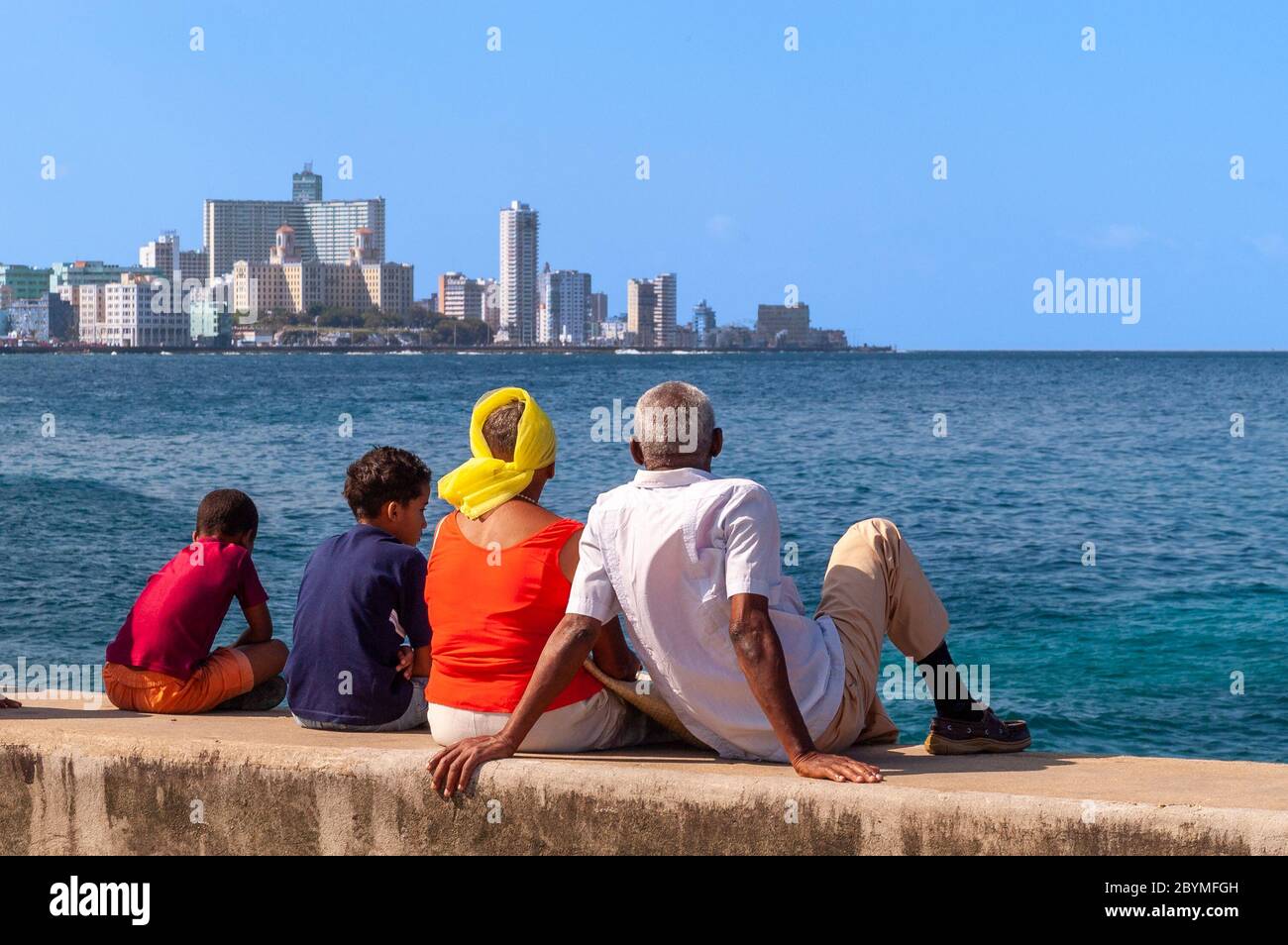 Grupo familiar sentado en la pared de el Malecón, la Habana, Cuba Foto de stock