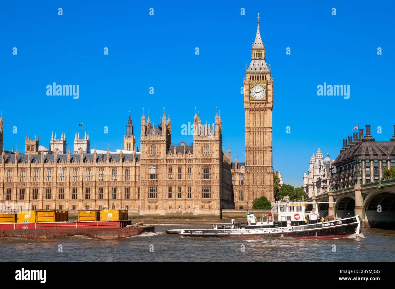 Barco de carga frente al Big Ben y las Casas del Parlamento en el río Támesis, Londres, Reino Unido Foto de stock