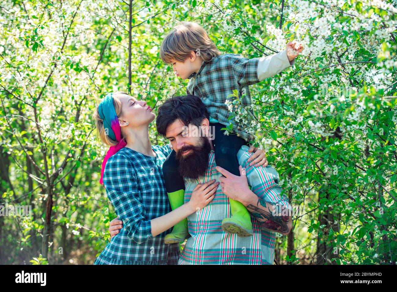 Familia caminando juntos por el campo de flores de primavera. Familia feliz pasando tiempo juntos en el jardín. Familia caminando en el campo agrícola. Foto de stock
