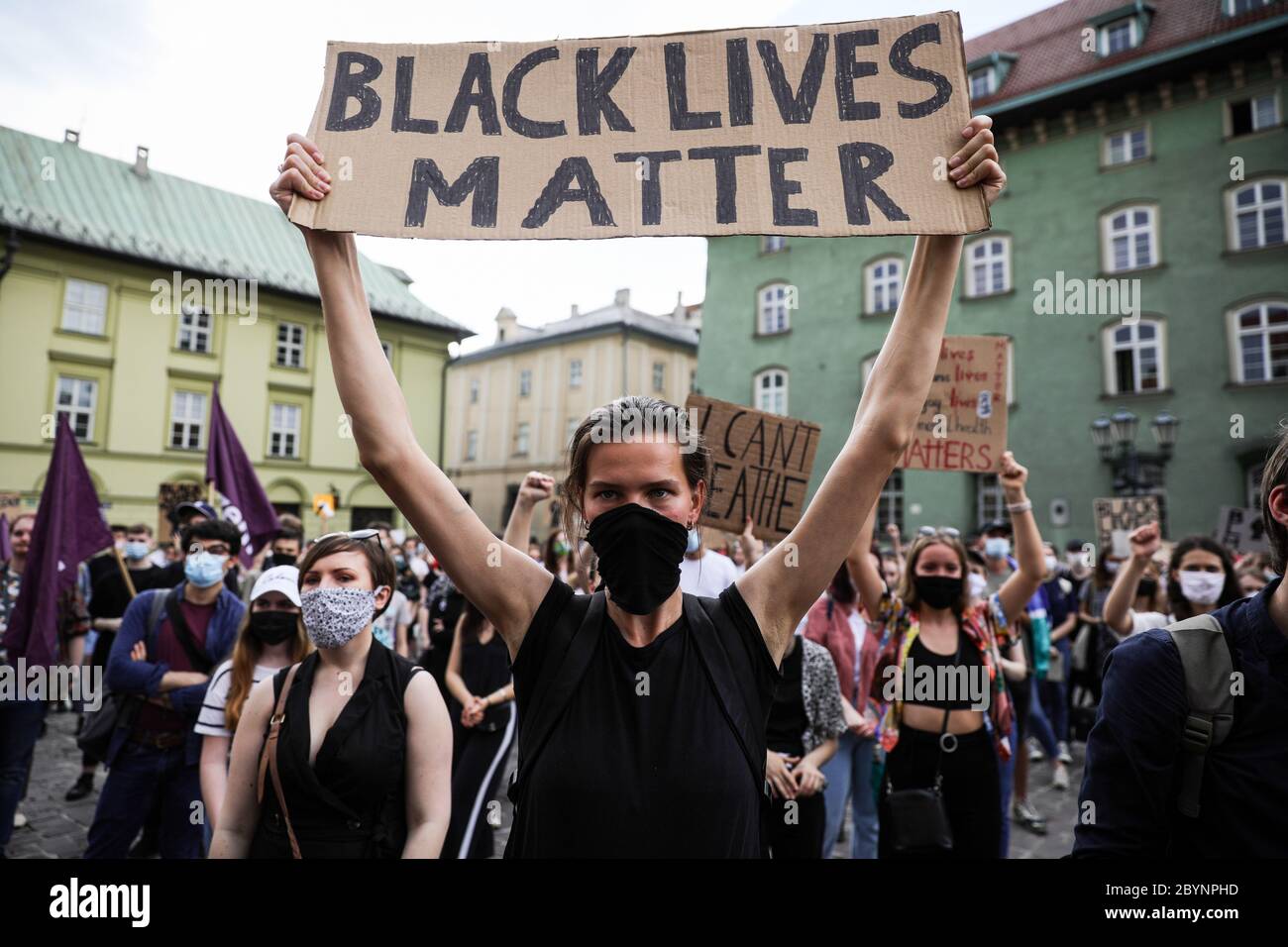 La protestera femenina en una máscara médica sostiene pancartas con lemas que condenan el racismo durante la protesta de "vidas negras" en Cracovia, la ciudad más grande de so Foto de stock