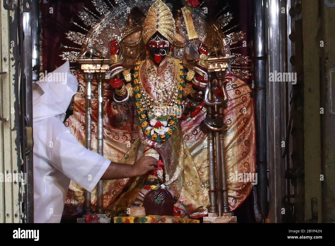 Kolkata, India. 10 de junio de 2020. Sacerdote hindú con kit PPE lleva a  cabo rituales frente al ídolo de la deidad hindú Kali en el templo de  Dakshineswar Kali antes de