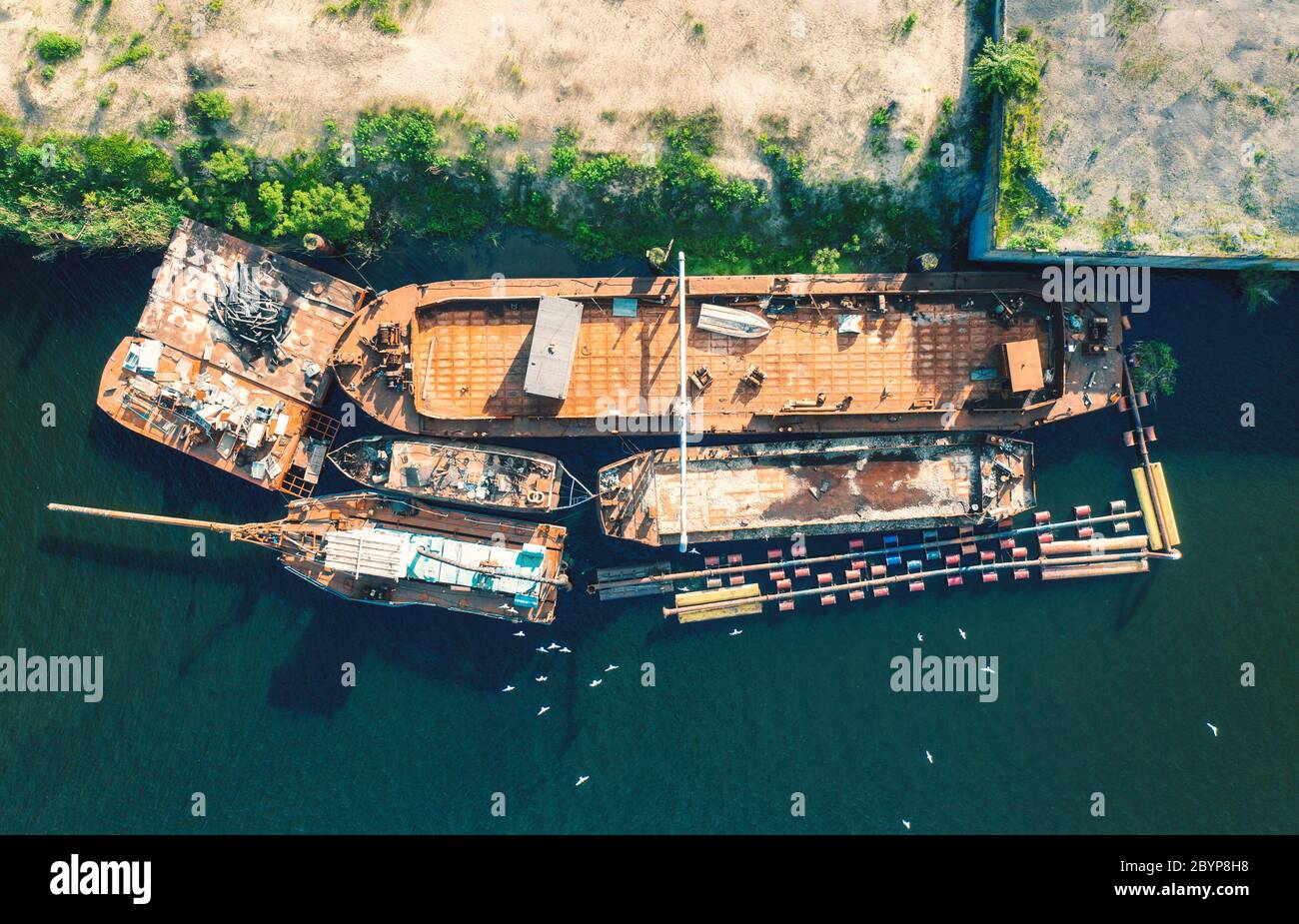 Vista aérea de viejos barcos oxidados y barcos en el mar al atardecer Foto de stock