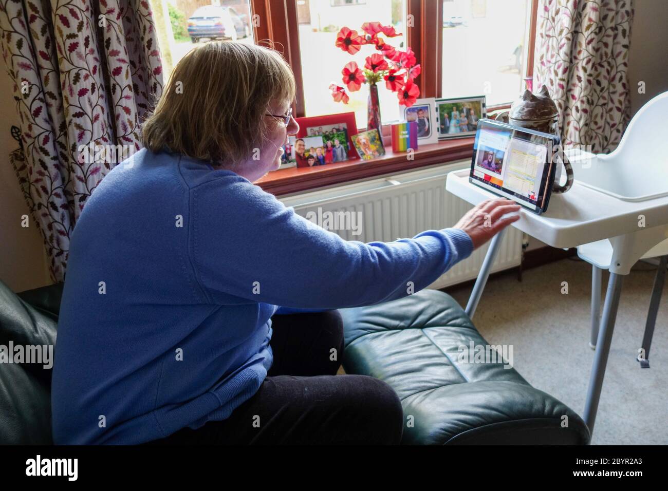 Mujer en su 60 ª usando video llamada (Zoom) con familiares durante la crisis del Coronavirus Foto de stock