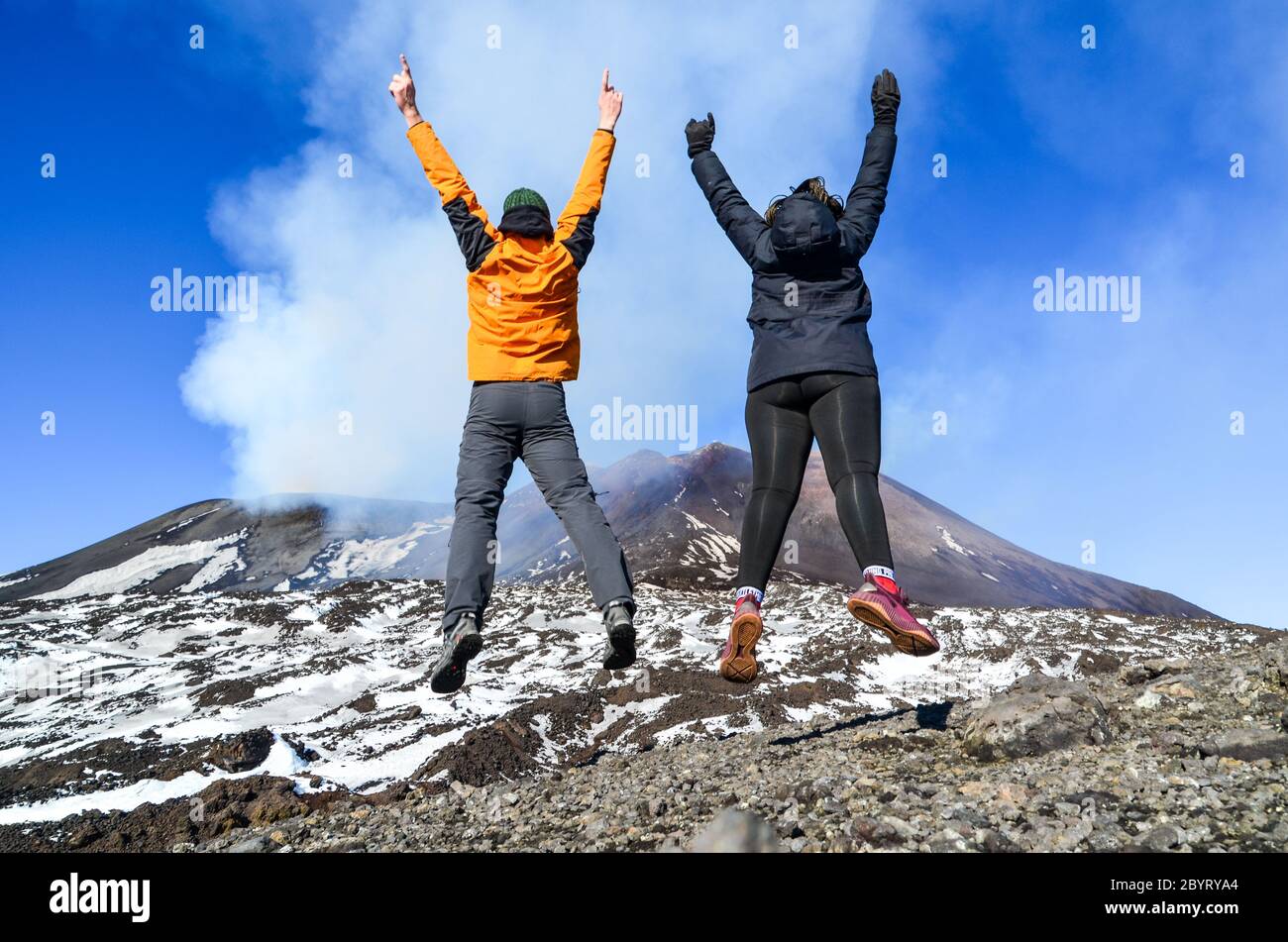 Un par de turistas saltando sobre el Monte Etna, Sicilia, Italia Foto de stock
