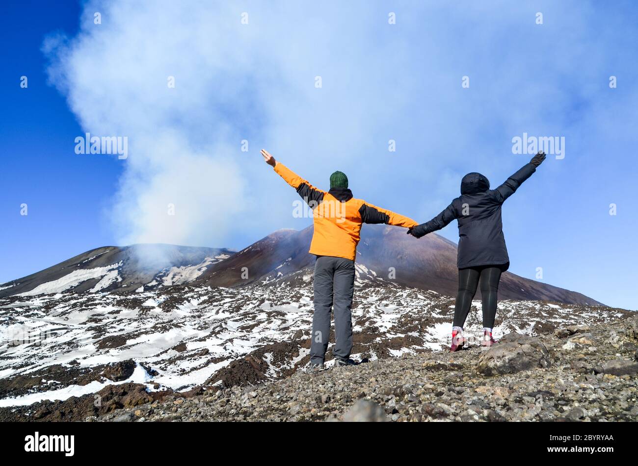 Pareja sosteniendo las manos en la cima del Monte Etna, Sicilia, Italia, el volcán activo estalló al día siguiente Foto de stock
