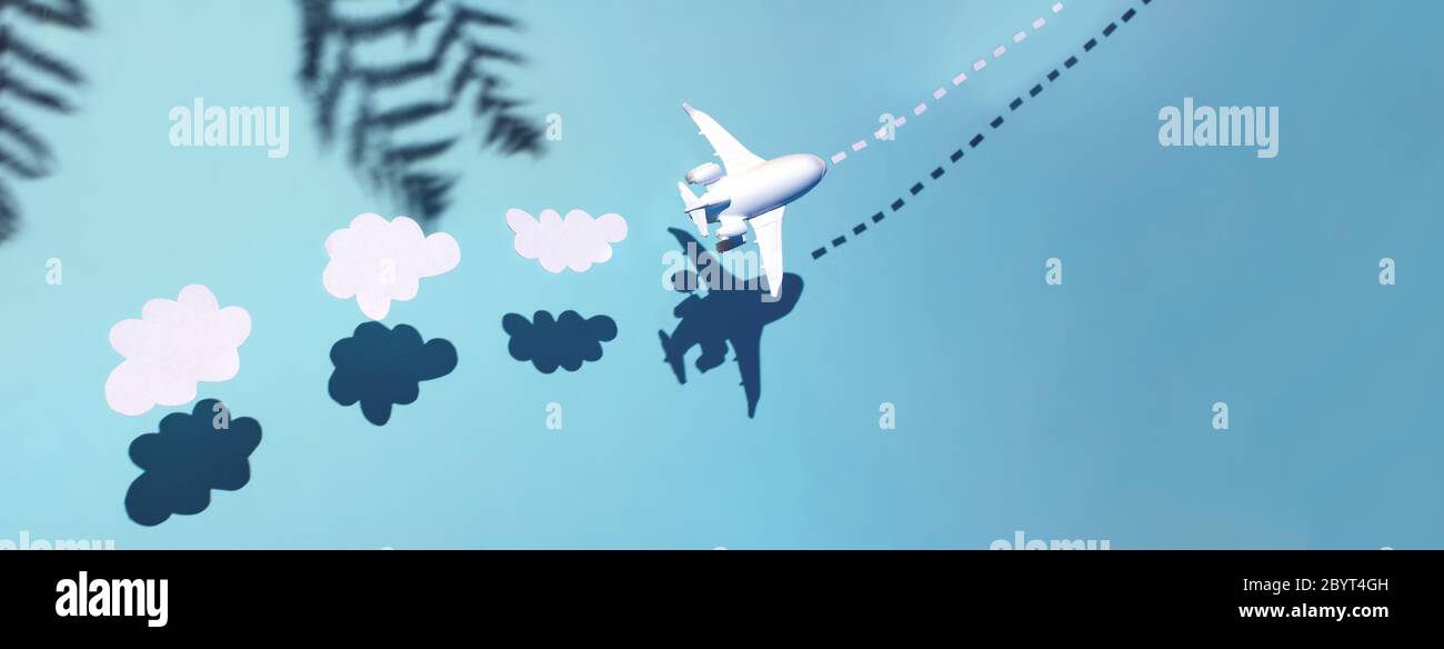 El avión blanco está volando a través del océano. Detrás de él hay nubes y palmeras. Concepto de restauración de vuelos después de la cuarentena y la apertura de fronteras Foto de stock