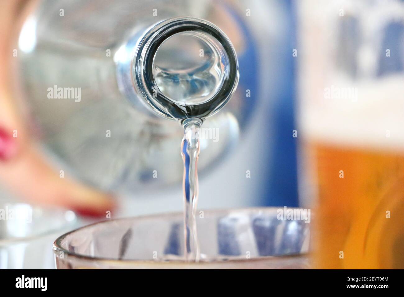 verter agua con una botella a un concepto de vidrio Foto de stock
