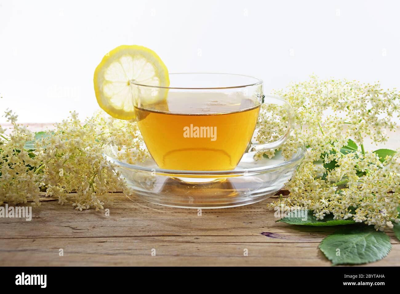 té de flor de arándanos con limón y algunas flores sobre una mesa de madera rústica sobre un fondo blanco, remedio casero contra el frío y la fiebre, espacio de copia Foto de stock