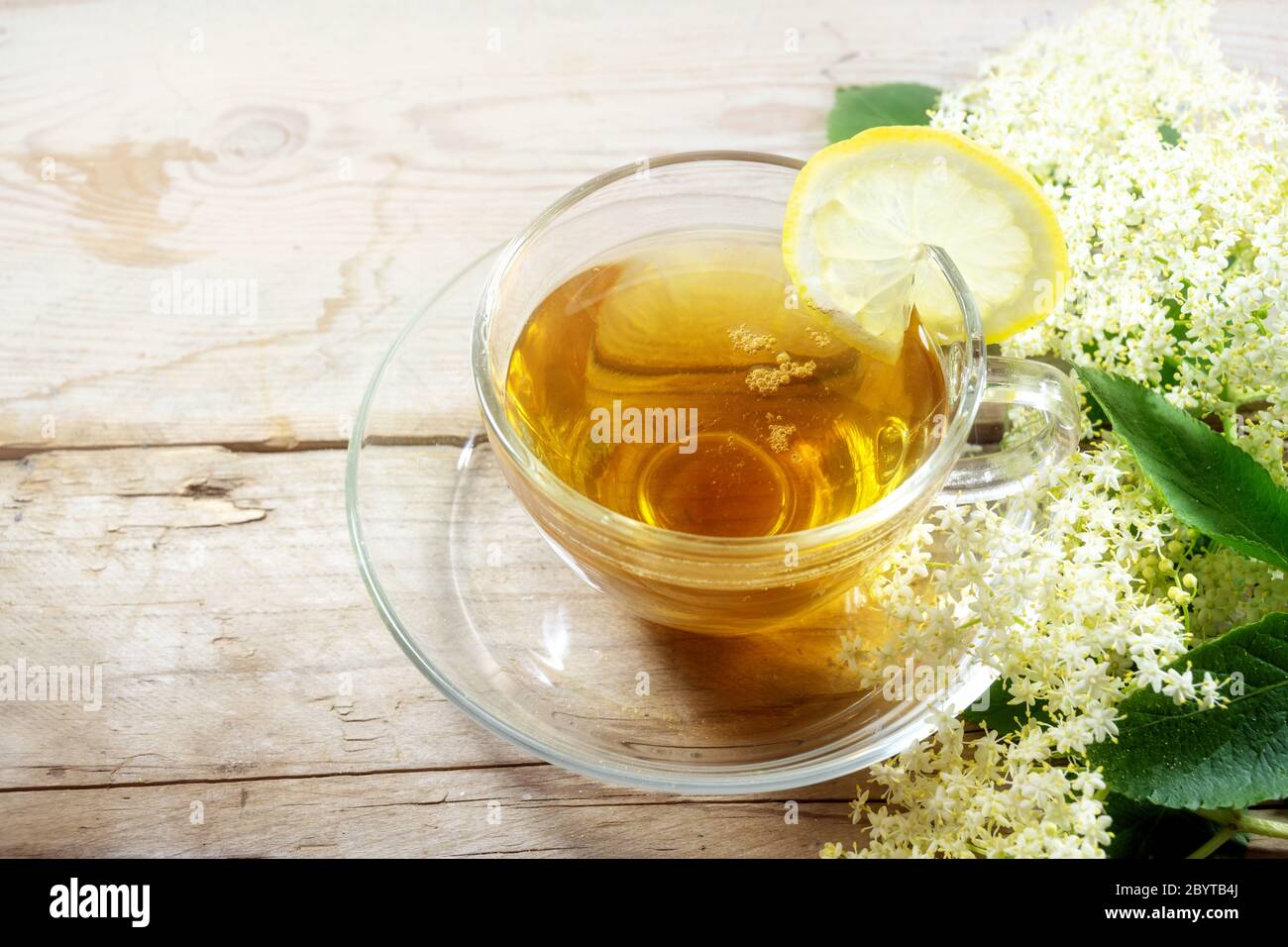 Té de flor de Elderflower con limón y algunas flores en una mesa de madera rústica, remedio casero natural para la limpieza de la sangre y contra el frío y la fiebre, espacio de copia, Foto de stock