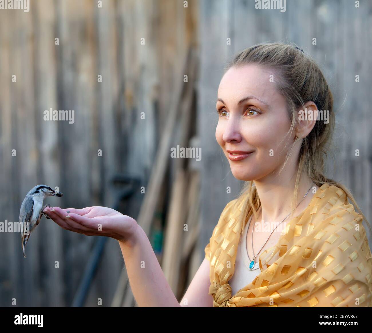 Hermosa mujer alimenta un pájaro de una mano Foto de stock