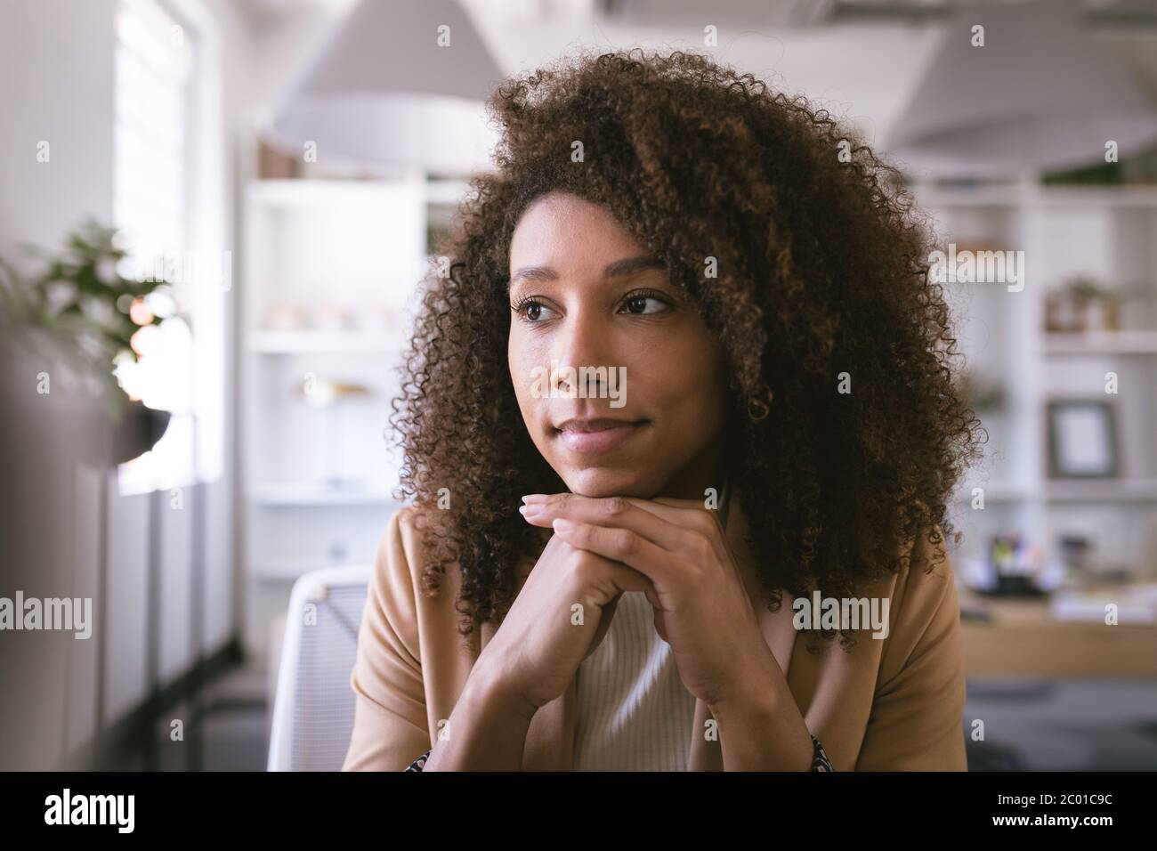 Retrato de una mujer de negocios de raza mixta pensando y sonriendo Foto de stock