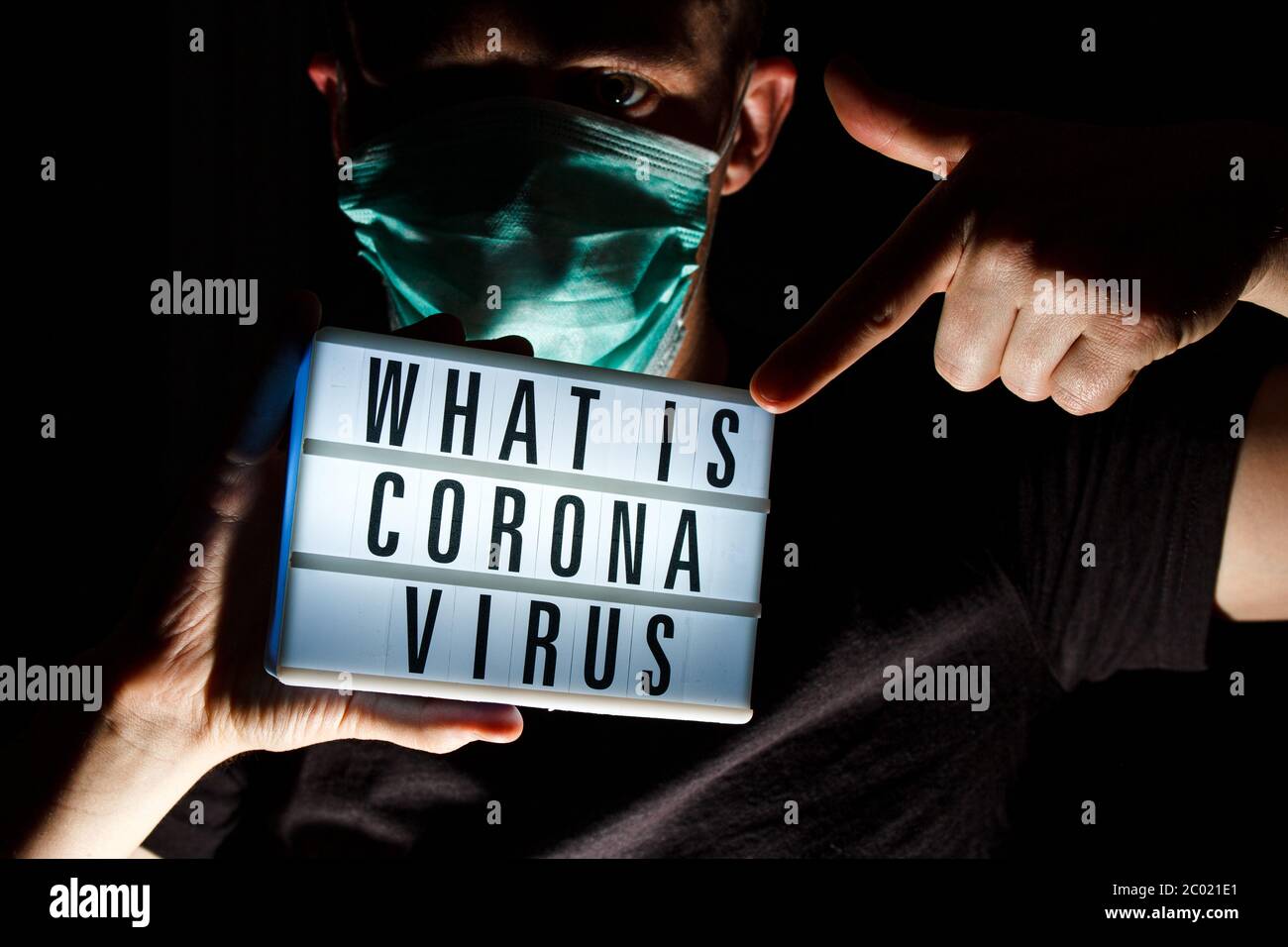 Hombre con máscara protectora tarjeta de retención con texto sobre la enfermedad del Coronavirus. ¿Qué es el Coronavirus? 2019 - nCoV, brote del virus Covid-19. Foto de stock