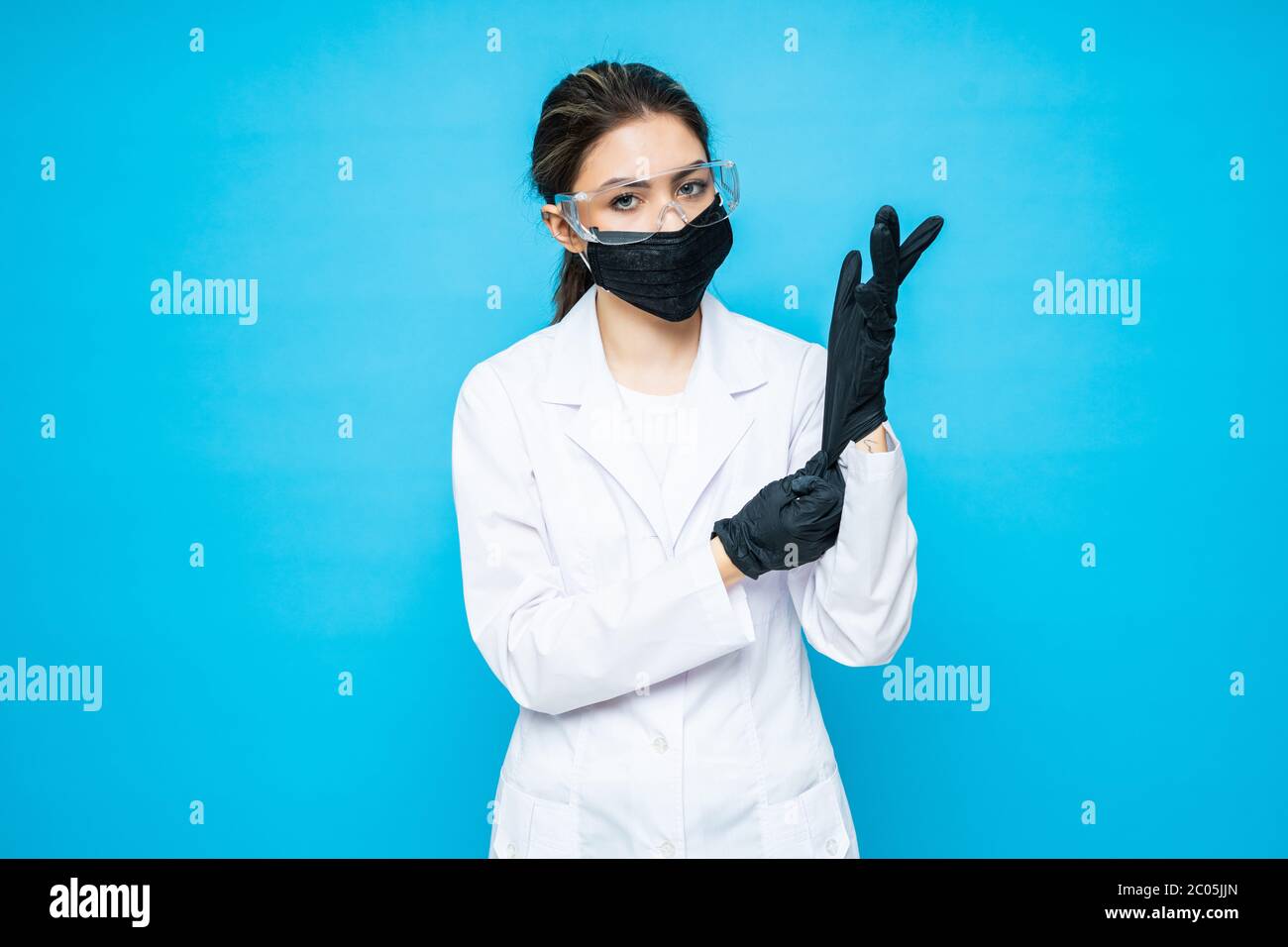 Mujer doctor poniendo guantes médicos de látex azul sobre fondo azul.  Cirujano usando guantes antes de la cirugía en el quirófano Fotografía de  stock - Alamy