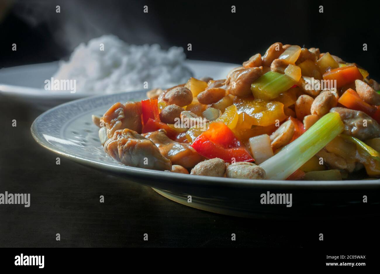 Pollo con jicama, cacahuetes y otras verduras como cebolla y zanahorias,  con un plato de arroz al vapor en el fondo, concepto de comida cantonesa  China Fotografía de stock - Alamy