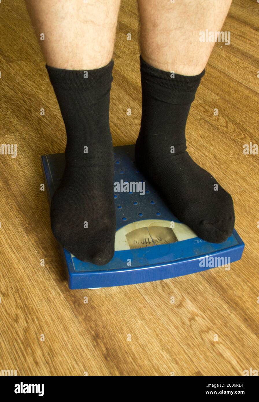 Piernas de hombre en calcetines negros se levantan en una balanza mecánica  de color azul (vista frontal Fotografía de stock - Alamy