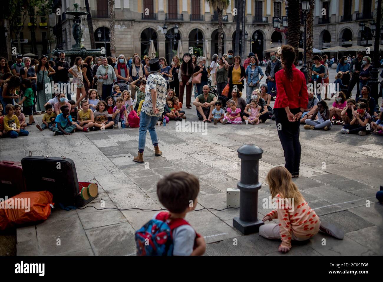 11 de junio de 2020, Barcelona, Cataluña, España: Los vecinos del Barrio Gótico se reúnen mientras disfrutan de un espectáculo de teatro callejero en el popular punto turístico de la Plaza Real de Barcelona. A medida que avanza la desafinación gradual, los barceloneses disfrutan de lugares de la ciudad que solían ser llenos por turistas antes de la crisis pandémica del coronavirus. Unión Europea pide abrir las fronteras interiores para el 15 de junio, el gobierno español tiene la intención de esperar hasta el 1 de julio. Crédito:Jordi Boixareu/Alamy Live News Foto de stock