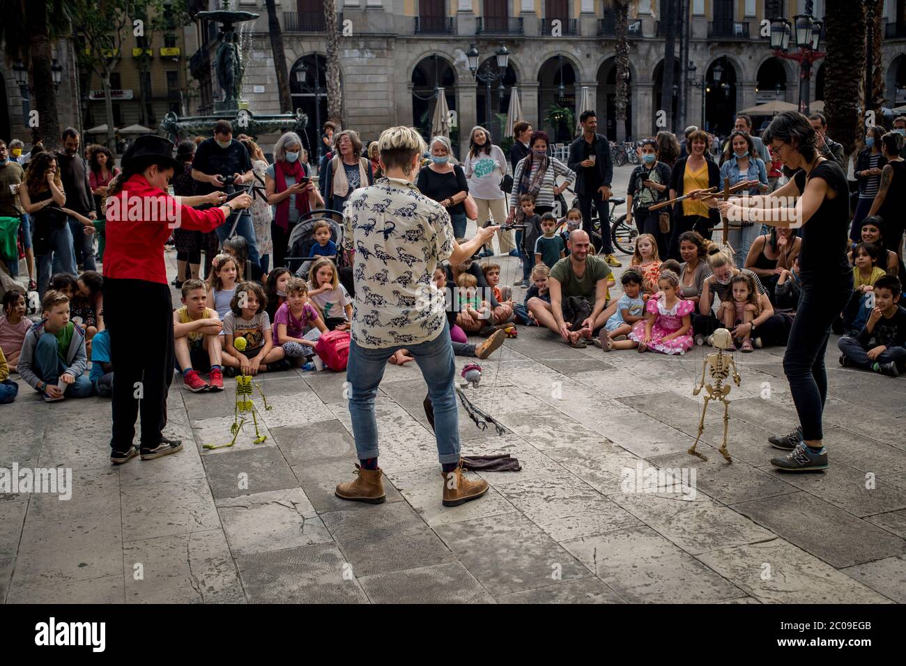 11 de junio de 2020, Barcelona, Cataluña, España: Los vecinos del Barrio Gótico se reúnen mientras disfrutan de un espectáculo de teatro callejero en el popular punto turístico de la Plaza Real de Barcelona. A medida que avanza la desafinación gradual, los barceloneses disfrutan de lugares de la ciudad que solían ser llenos por turistas antes de la crisis pandémica del coronavirus. Unión Europea pide abrir las fronteras interiores para el 15 de junio, el gobierno español tiene la intención de esperar hasta el 1 de julio. Crédito:Jordi Boixareu/Alamy Live News Foto de stock