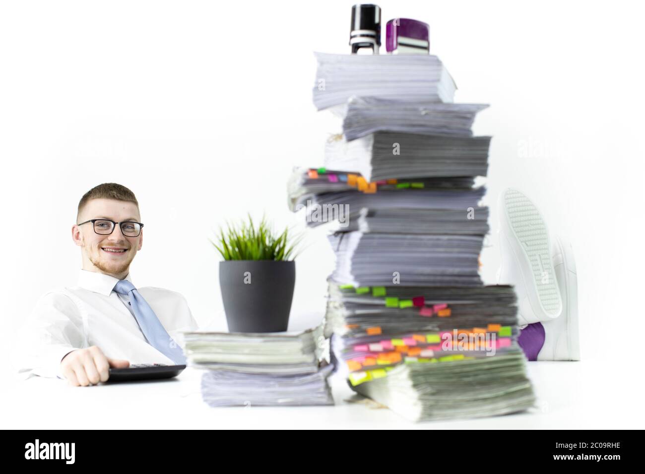 Un trabajador de oficina feliz se sienta con sus piernas en la mesa, lleno  de papeles y sellos Fotografía de stock - Alamy
