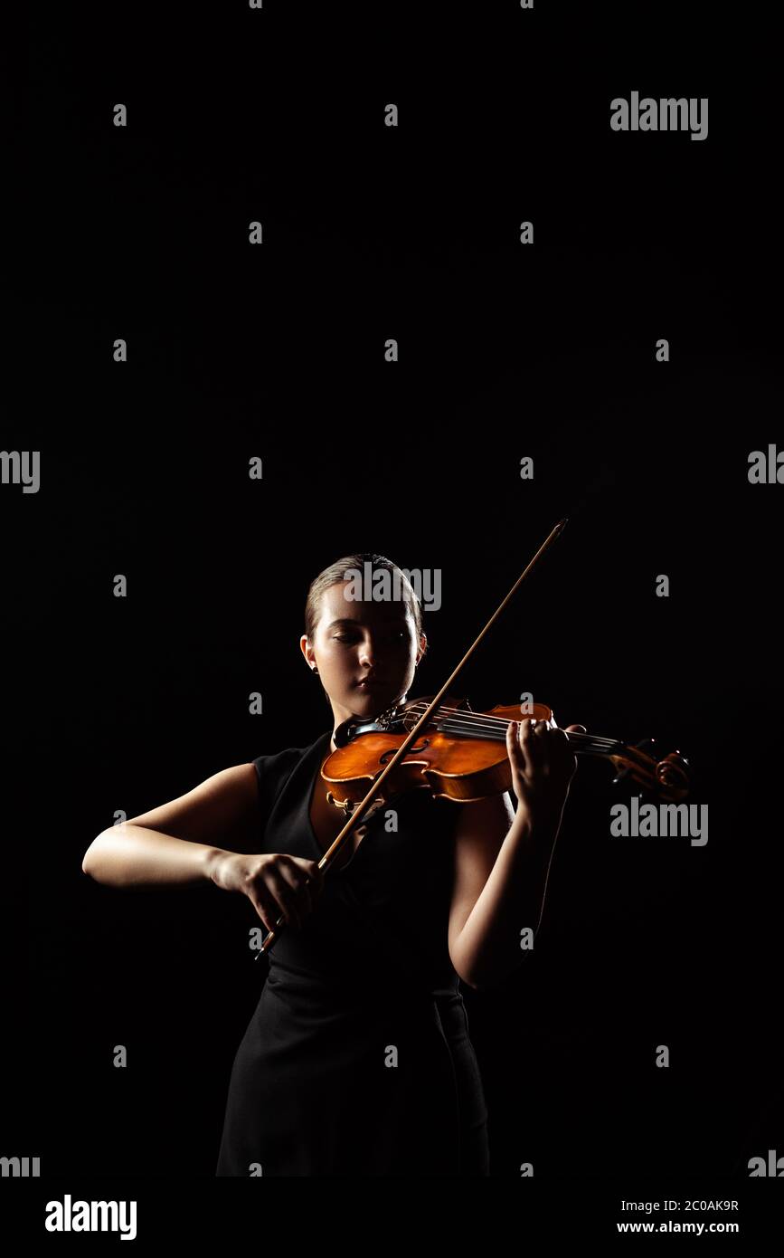 hermoso músico profesional tocando sinfonía en instrumentos musicales aislados en negro Foto de stock