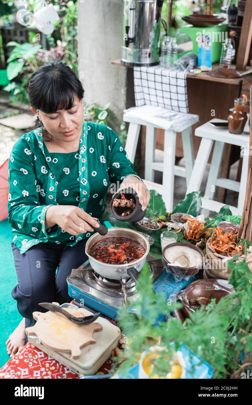 Las mujeres asiáticas hacen medicamentos a base de hierbas hacen recetas tradicionales de hierbas javanesas hirviendo Foto de stock