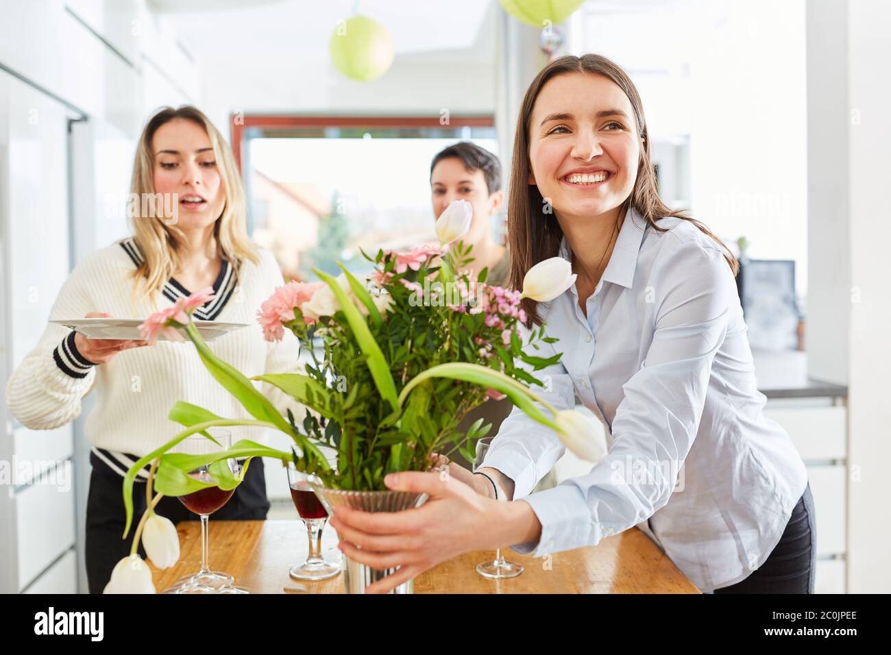 Mujer decorando mesa con novias y poniendo para el almuerzo en cocina compartida Foto de stock