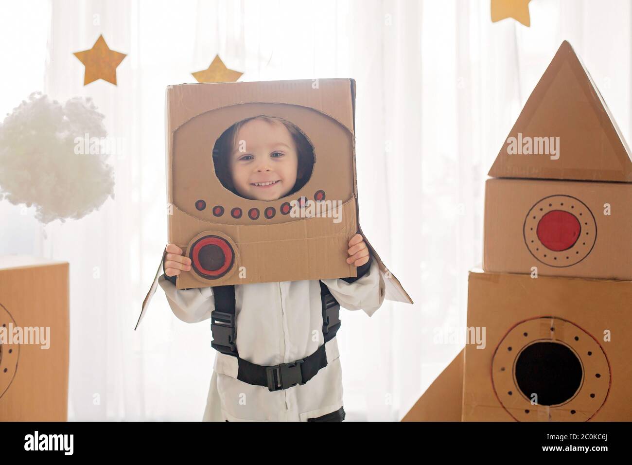 Dulce niño pequeño, vestido como astronauta, jugando casa con cohete de y casco hecho a mano de la caja Fotografía de stock - Alamy