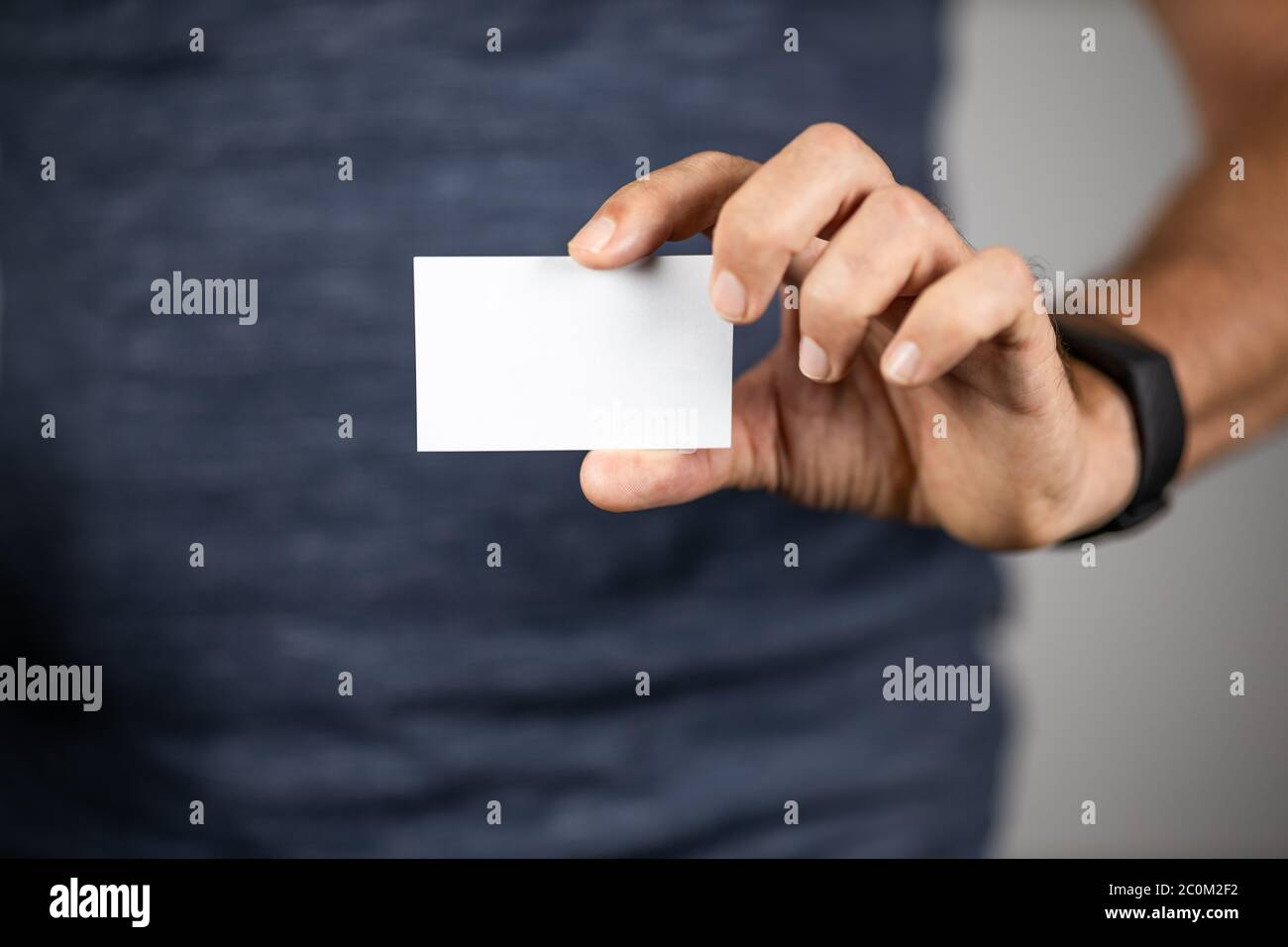 Hombre sosteniendo un papel en blanco del tamaño de una tarjeta de visita. Enfoque selectivo. Foto de stock