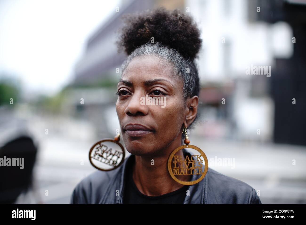 Una mujer con pendientes que dicen Black Lives importa en la presentación de una cartelera BLM Westminster Bridge Road, Londres. Foto de stock