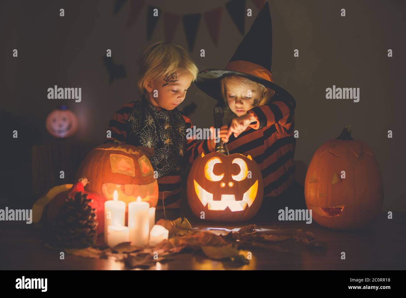 Adorables niños, niño y niña, jugando con calabaza tallada de Halloween y decoración en casa Foto de stock