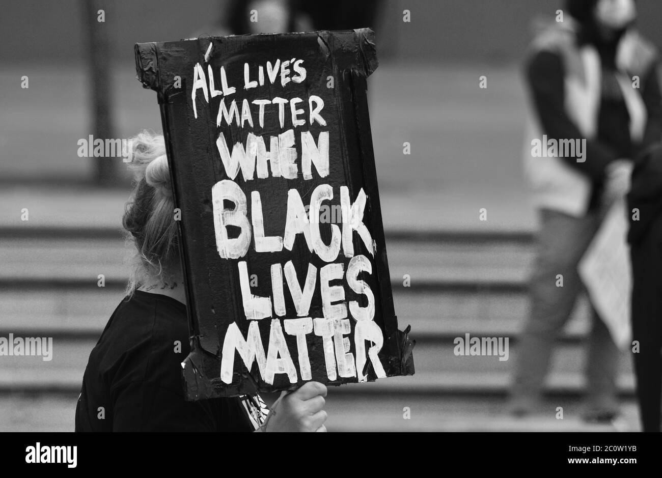 Una señal / cartel que dice "todas las vidas importan cuando Las vidas negras importan' siendo retenidas por un manifestante en un Protesta británica de la BLM en 2000 Foto de stock