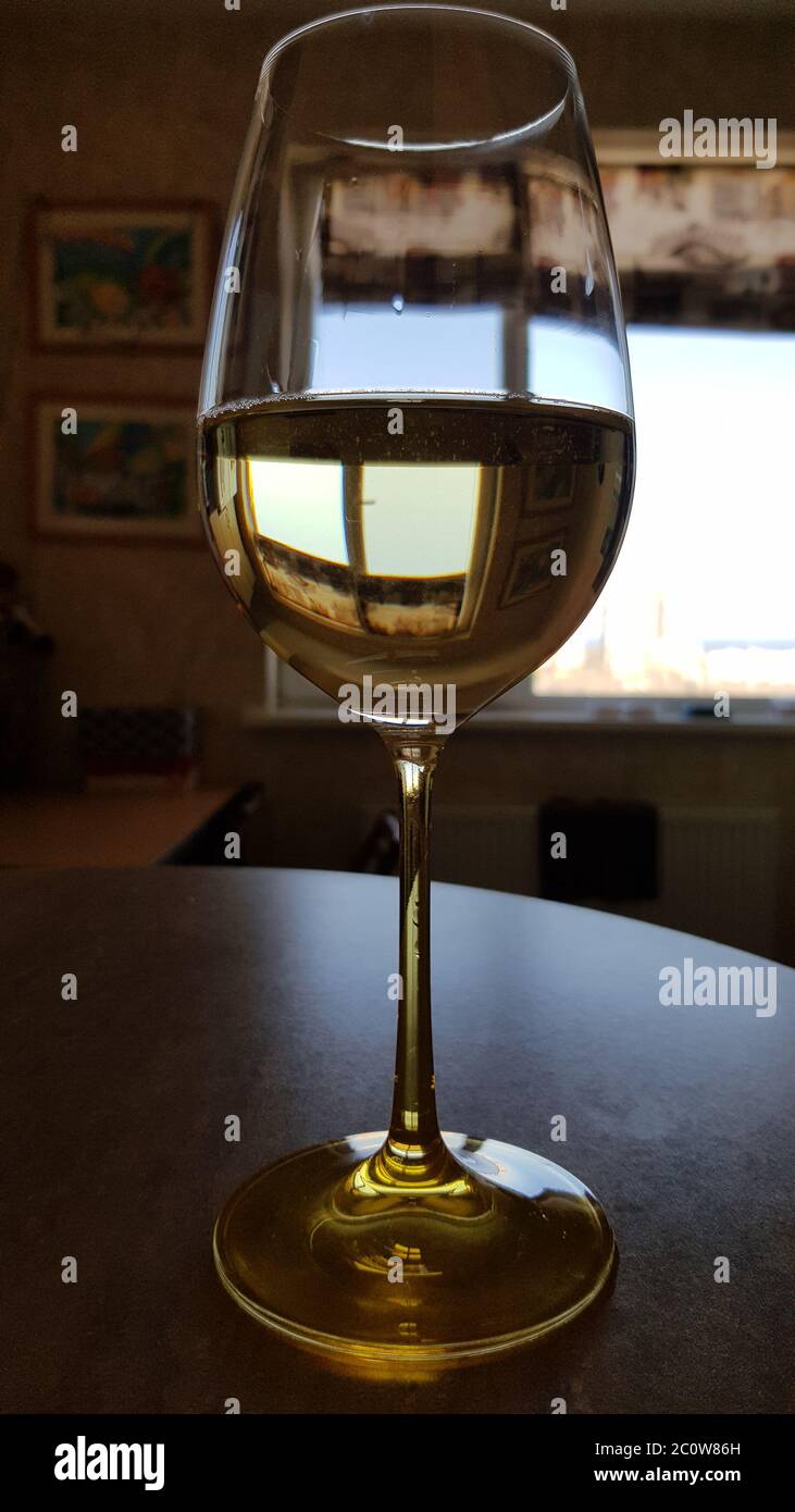 Primer plano de cristal transparente sobre mesa. Cristalería para vino blanco en frente de la ventana. Bebida alcohólica de verano Foto de stock
